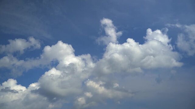 Horizontal movement of white clouds across a blue sky on a sunny day