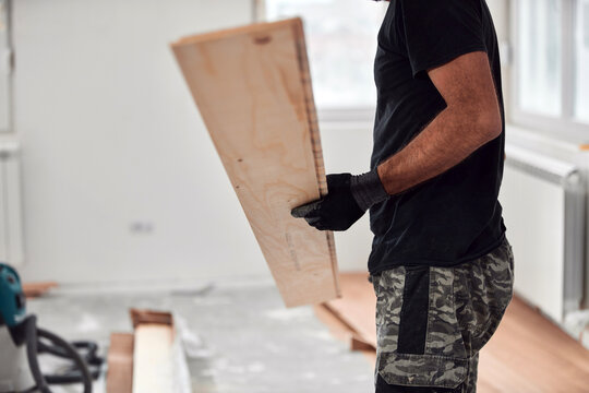 Professional handyman installing laminate flooring in a new apartment.