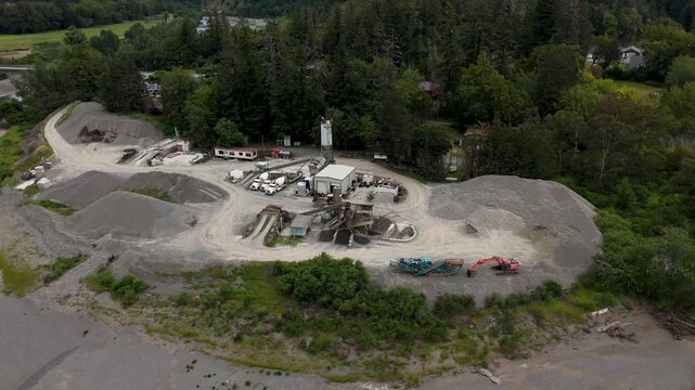Aerial view of a gravel quarry and industrial site with heavy machinery, aggregate piles, and surrounding forest in Garberville, California, United States.