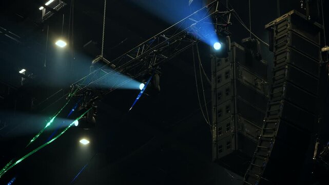 Professional audio speakers and stage lighting gear hanging at a music event