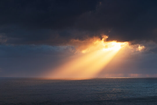 Dramatic Sun Rays over Sea Surface during Stormy Sunset over Madeira island Portugal