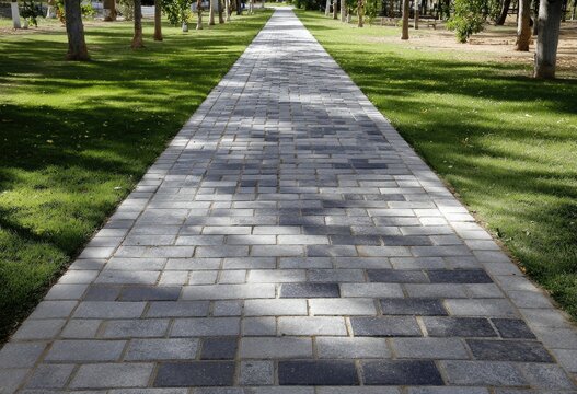 A long, paved path leads through a park with trees and grass
