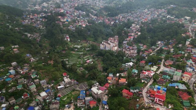 Scenic aerial overview of Baguio City in Benguet, Philippines with dense hillside neighborhoods, mountain terrain, winding roads, and tropical urban landscape