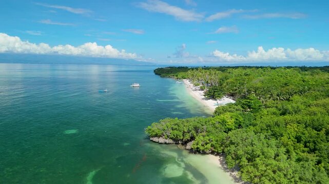 Aerial pull-back revealing full curve of Paliton Beach with outrigger bangka boats, emerald water, mangroves, coral reef patches, and tropical forest on Siquijor Island, Philippines
