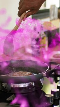 Vertical video: Lit burner heating, senior cook pressing patty for content, pink smoke wrapping pan