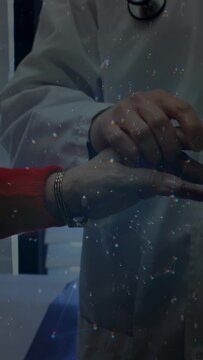 Vertical video: Doctor palpating patient wrist, hologram sphere expanding as guide for pulse check