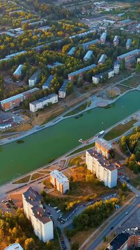 Vertical video. Russia, Votkinsk . Drone footage of the city embankment and Votkinsk Reservoir at sunset, warm golden light over water and Soviet-era apartment blocks. Drone footage. Rich colors
