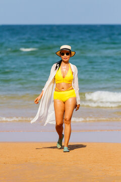 Woman with yellow bikini walk on beach