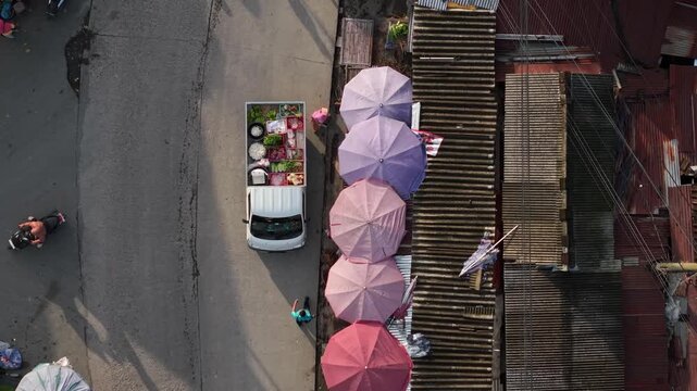 Aerial view of Traditional Market Pasar Kembang Klaten with a white truck loaded with fresh vegetables and colorful umbrellas on a street in Kemalang, Central Java, Indonesia.