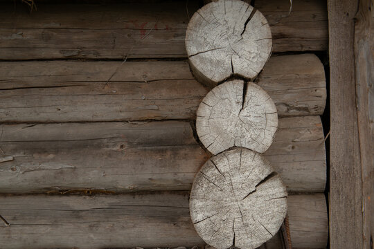 Rustic log cabin detail: weathered wooden logs with exposed tree rings &mdash; close-up of aged timber texture and split log ends