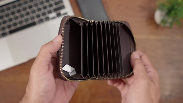 A person opening an empty wallet with no cash inside, representing poverty, financial stress, unemployment, and money management issues.