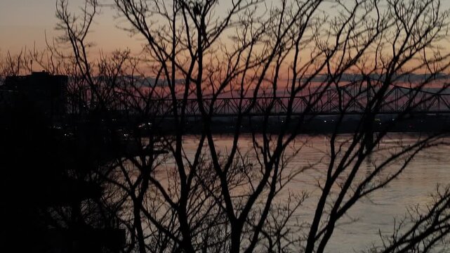 Aerial view of the George Rogers Clark Memorial Bridge over the Ohio River during a vibrant sunset in Louisville, Kentucky, United States.