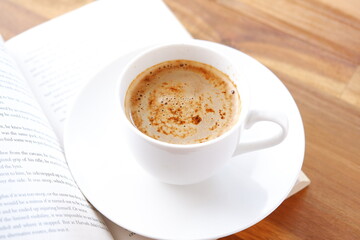 Fototapeta premium ページを開いたペーパーバック（洋書）とコーヒーの入ったコーヒーカップで、コーヒーを飲みながら読書を楽しんでいるイメージ 