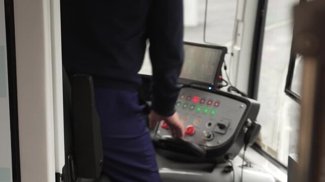 Train driver enters the cabin train and sits next to the control panel. Modern electric tram control panel with buttons and monitor in front of the windshield.