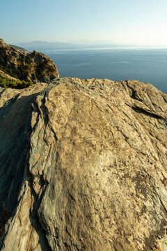 Coastal landscape featuring a rugged rocky cliff overlooking the vast Mediterranean Sea under a clear sky, perfect for travel and tourism in North Corsica, with ample copy space.
