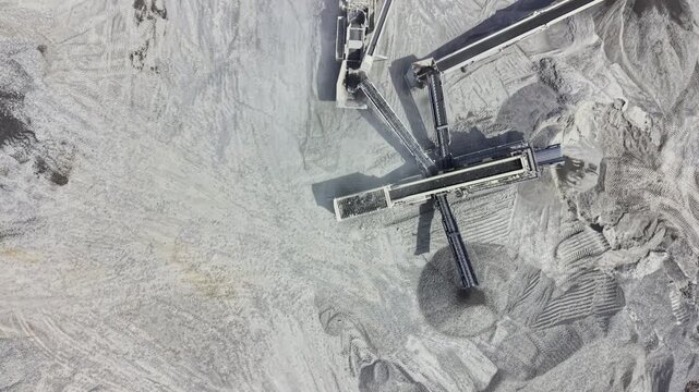 Aerial view of a granite quarry showing machines working to extract large stone blocks from the earth. The scene reveals the layout of machinery and tools in use during quarrying activities.
