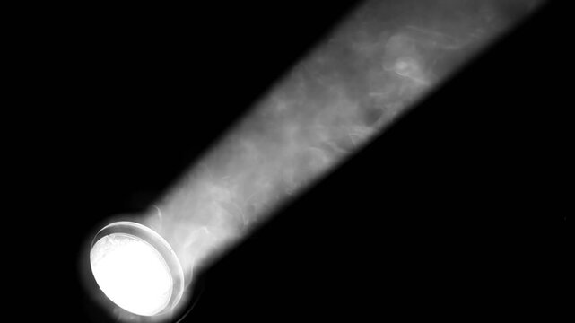 LED stage spotlight with rising smoke in dark atmosphere.