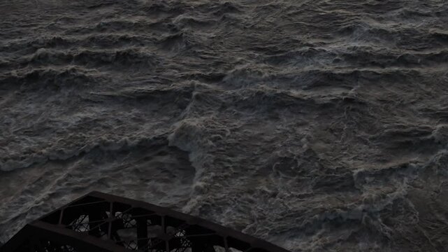 Aerial view of turbulent muddy river water rushing past a dark metal bridge structure in Louisville, Kentucky, United States.