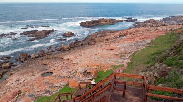 Hikers walk down wooden stairs along Robberg Nature Reserve hiking trail