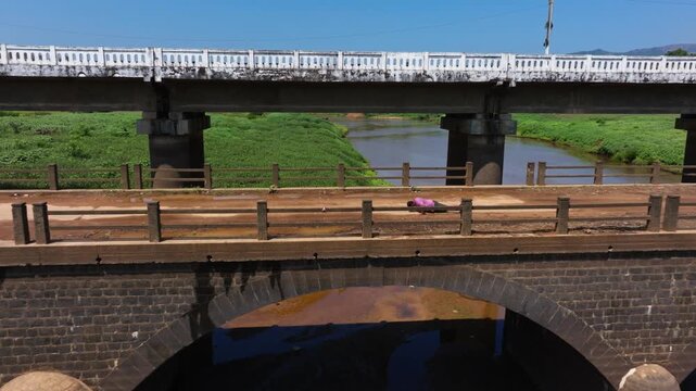 Person doing push ups on old Hardoor Bridge, harangi river and greenery at Anjanageri Bettageri, coorg, Karnataka, india. day time, push in shot, semi orbit shot, drone shot, 4k.