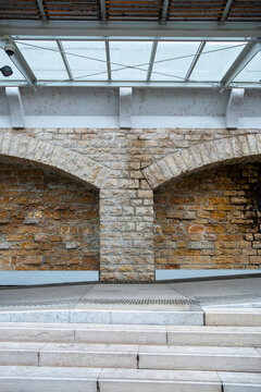 Stone wall and glass roof frame stairs in restored architecture, where arch texture, railing and interior structure define heritage access