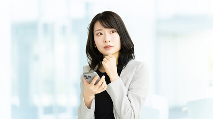 Fototapeta premium スマートフォンを見ながら考える女性・ビジネスウーマンのビジネスイメージ, Businesswoman Thinking While Using Smartphone