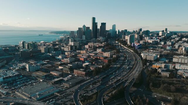 Aerial view of downtown seattle with busy freeway traffic and waterfront during golden hour, cinematic motion footage.
