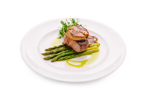 Beef tenderloin steak Rossini with foie gras and asparagus served on a white plate at a restaurant