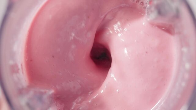 Strawberry and banana pink milkshake blended in blender with splashes. top view. slow motion. Healthy protein smoothie drink concept , food closeup