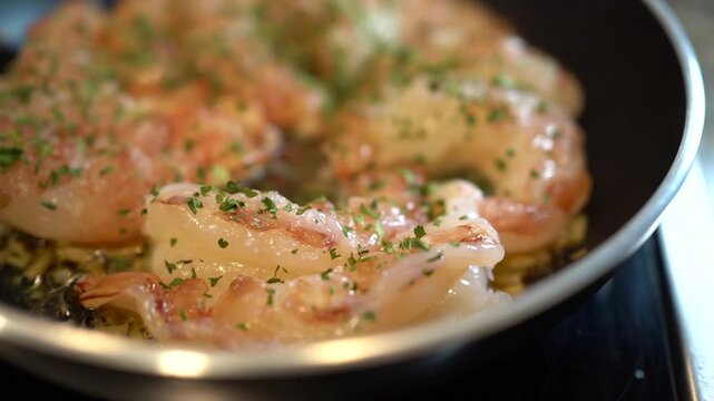 Shrimp saut ing in olive oil with garlic and parsley in a frying pan on the stove fresh, homemade seafood meal preparation