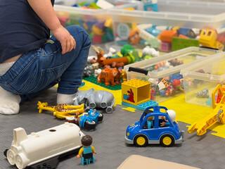 Fototapeta premium Child Playing on Floor with Toys and Storage Bins lego