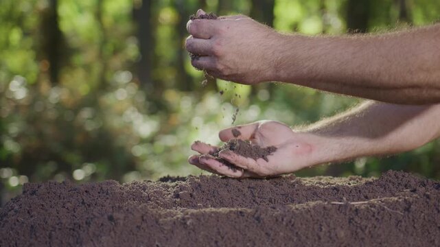 Earth and environment protection theme. Fertile soil in hands. Soil falling through hands. Closeup of dirt and clay in hands. Hands working with soil. Soil for planting. Melioration concept.
