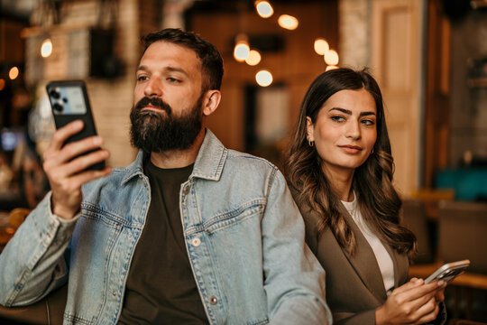 Couple experiencing phubbing during social interaction at cafe