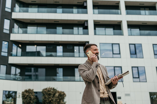 Businessman talking on phone walking outside modern building