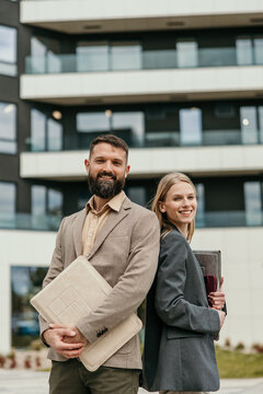 Business partners smiling standing back to back outdoors