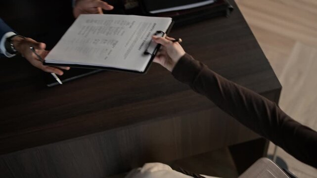 High angle shot of Caucasian woman giving signed documents to lawyer to check during divorce consultation in office