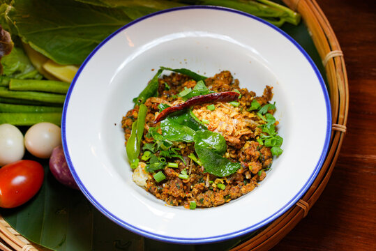 Spicy Minced Fish Salad with Fresh Herbs, Traditional Larb Pla Khua Served in White Bowl, Authentic Thai Roasted Fish with Chili and Mint