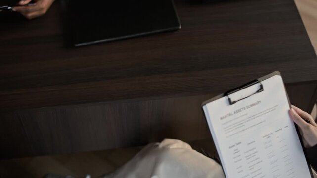 High angle shot of unrecognizable couple filling in marital assets summary during divorce consultation in office