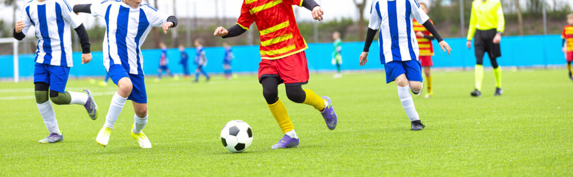 Wide Angle Shot of Junior Soccer Players in Red and Blue Stripes Competing on Green Grass Field - Youth Football Match Action and Player Movement