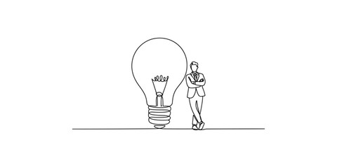 A man in a suit stands confidently next to a large light bulb © SR