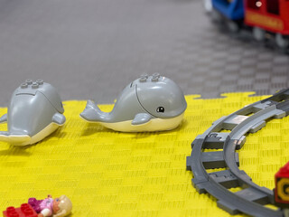 Fototapeta premium Toy whales on yellow playmat with train tracks lego
