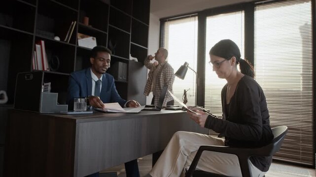 Medium shot of brunette woman signing settlement agreement while her spouse looking out of huge window