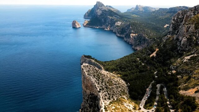 Aerial view of the rugged cliffs of Cap de Formentor overlooking the turquoise Mediterranean Sea and winding coastal roads Balearic Islands, Spain.