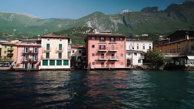 Colorful buildings line Lake Garda shore with mountains in Italy