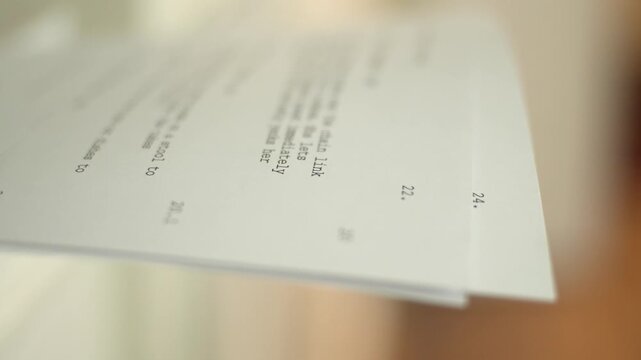 Close-up of printed script pages stacking as they come out of a printer. Visual of writing workflow, document production, and content creation in progress.
