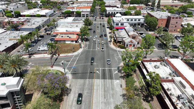 High aerial establishing shot of Harbor Boulevard in downtown Fullerton featuring nightlife attractions, commercial brick buildings, restaurants, tourists, and active city street scenery.