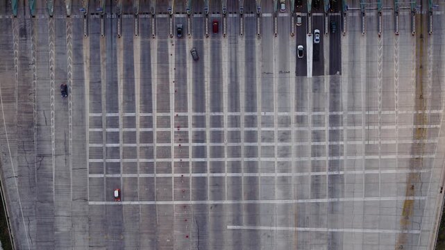 Aerial overhead of toll plaza structure with patterned lanes and light vehicle traffic flow, drone