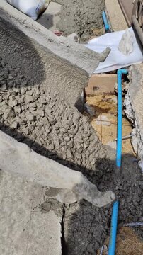 The liquid concrete is stopping flowing from the chute on the cement truck.	
