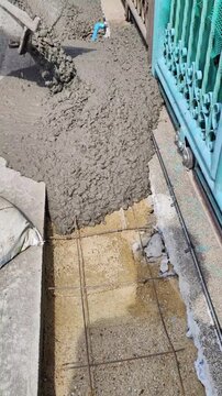 The liquid concrete is stopping flowing from the chute on the cement truck.	