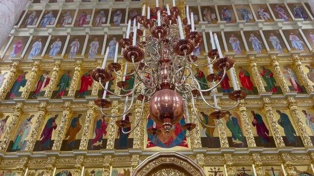 Tilt down inside the Assumption Cathedral, Astrakhan Kremlin. An ornate chandelier and golden iconostasis with Orthodox icons highlight Russian religious architecture and heritage